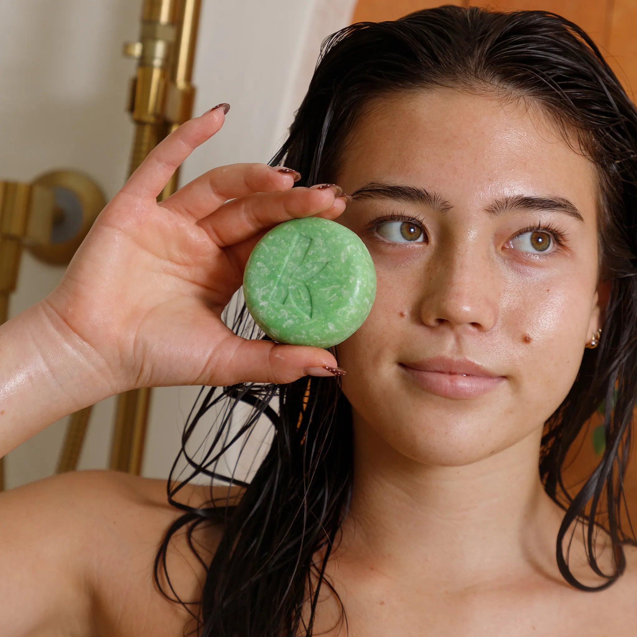 Person holding a olive oil shampoo bar in front of their face