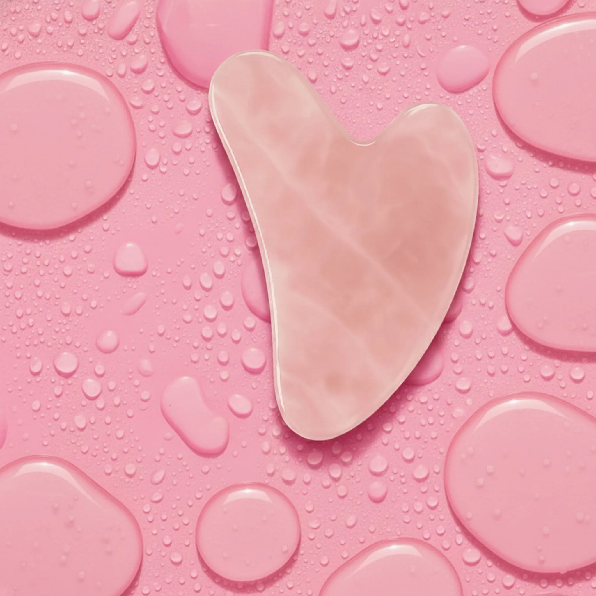 Rose gua sha tool on a pink textured background