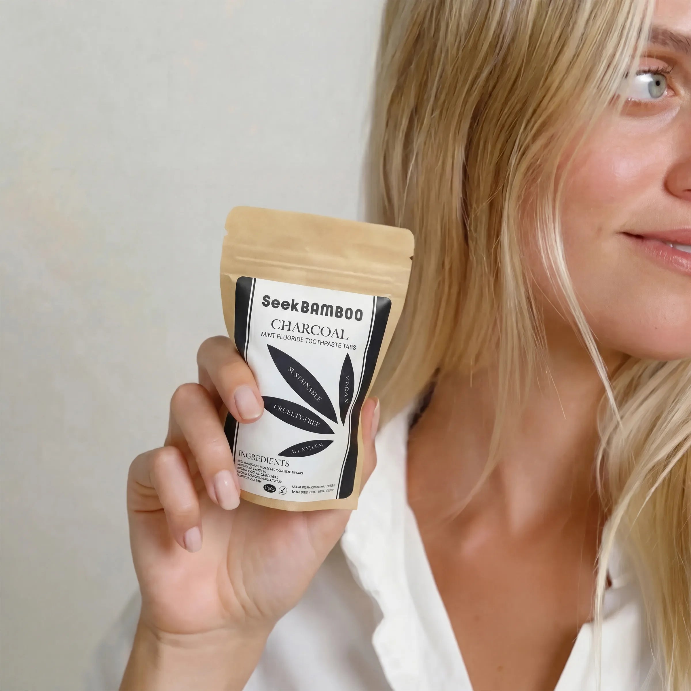 Woman holding a package of Seek Bamboo Charcoal on a plain background