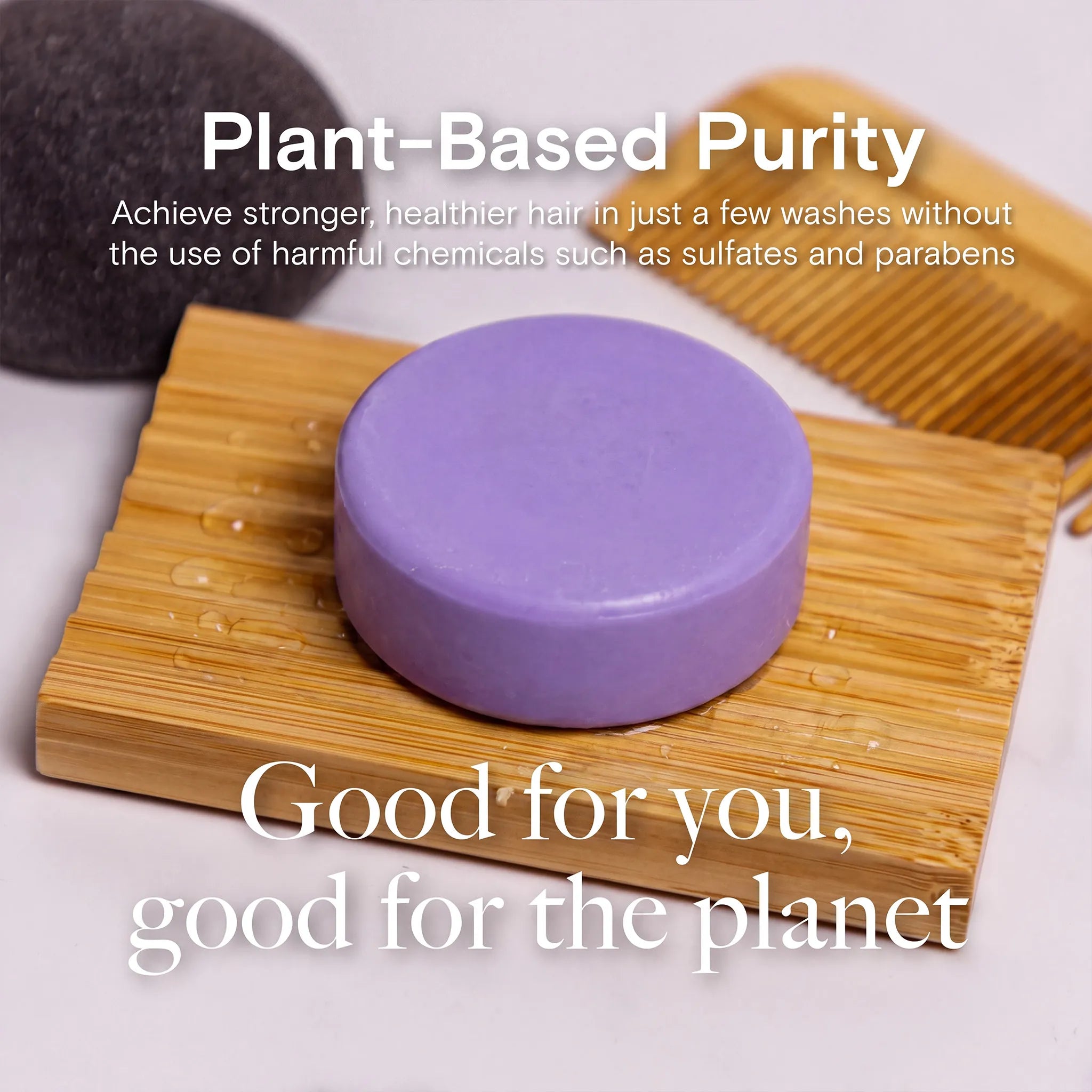 A round purple conditioner bar resting on a bamboo soap dish, with a wooden comb and a dark stone in the background. White text overlays read 'Plant-Based Purity' and 'Good for you, good for the planet'.