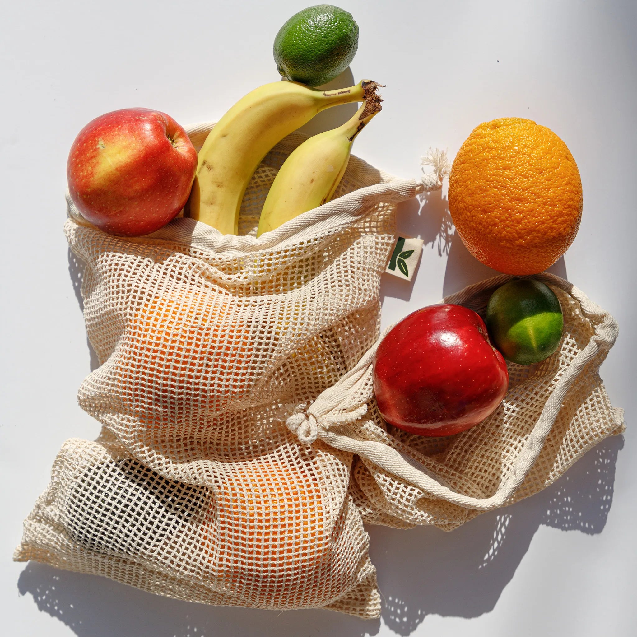 Reusable mesh produce bag with fruits on a white background
