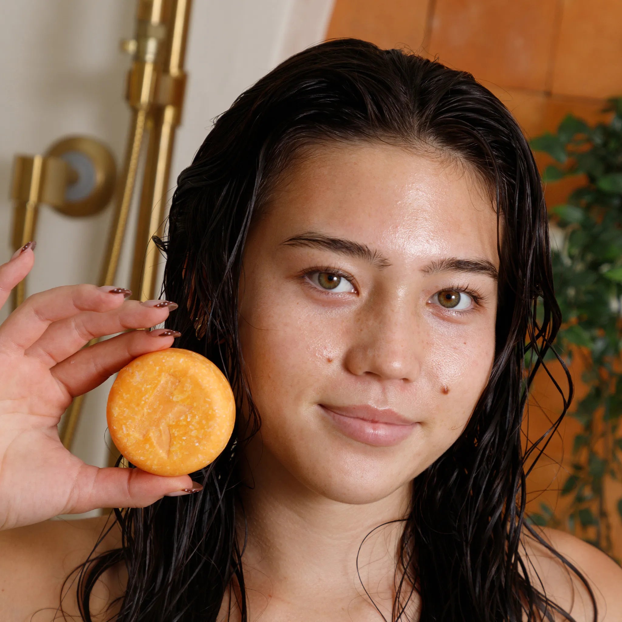 Woman holding a honey shampoo bar in front of her face with a blurred background