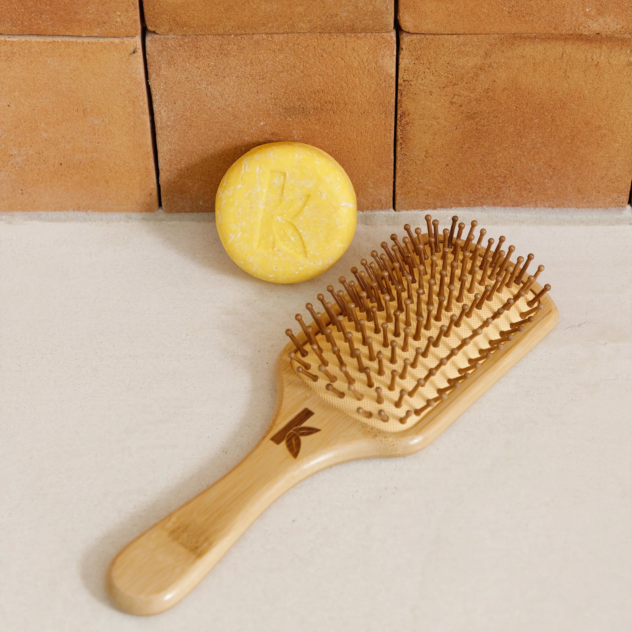 Turmeric Shampoo bar next to Bamboo Hairbrush