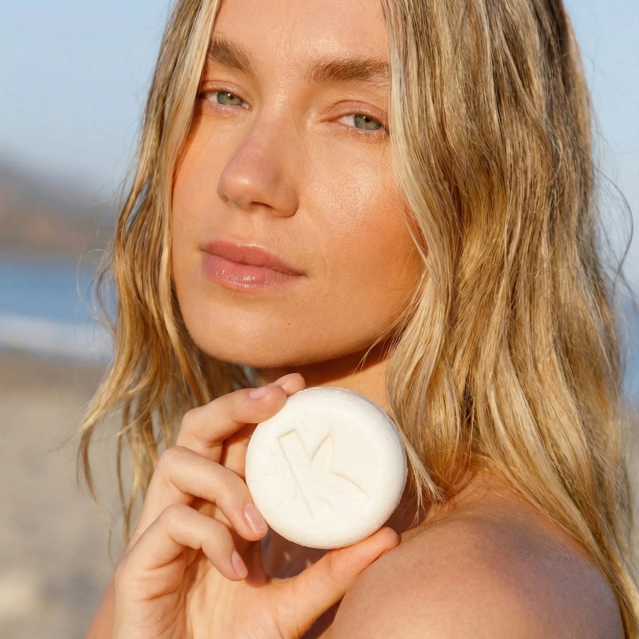 Woman holding a white ball on a beach with a clear sky