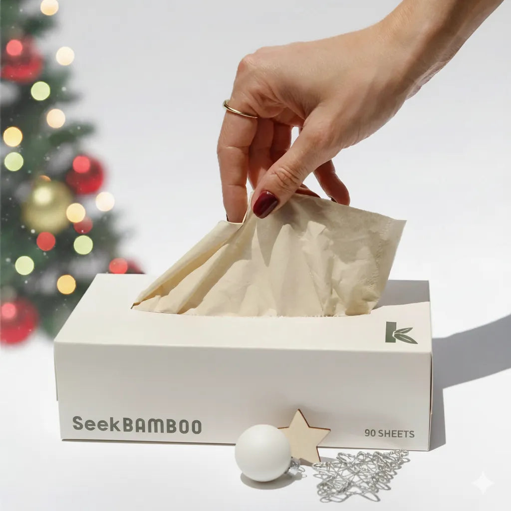 Hand pulling a bamboo tissue from a box labeled 'Seek Bamboo' with a Christmas tree in the background.