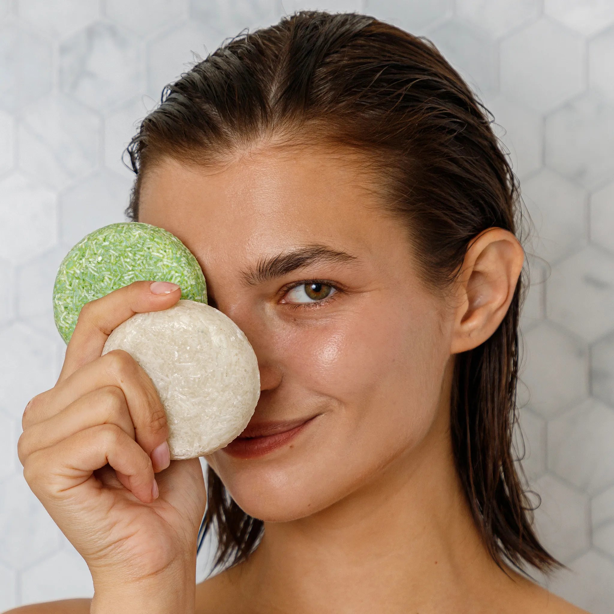 woman holding a rice shampoo bar and an olive shampoo bar