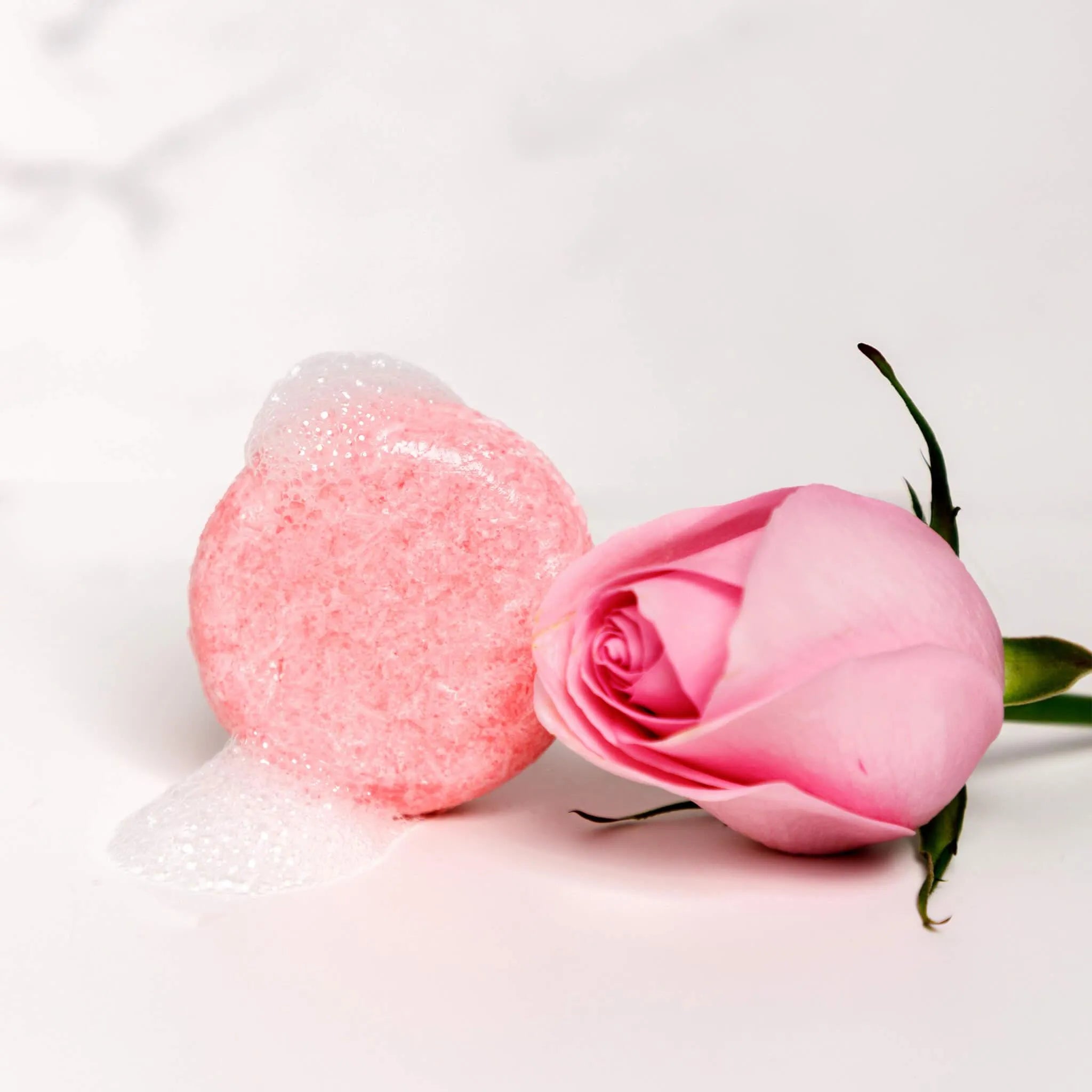 rose shampoo next to rose petals
