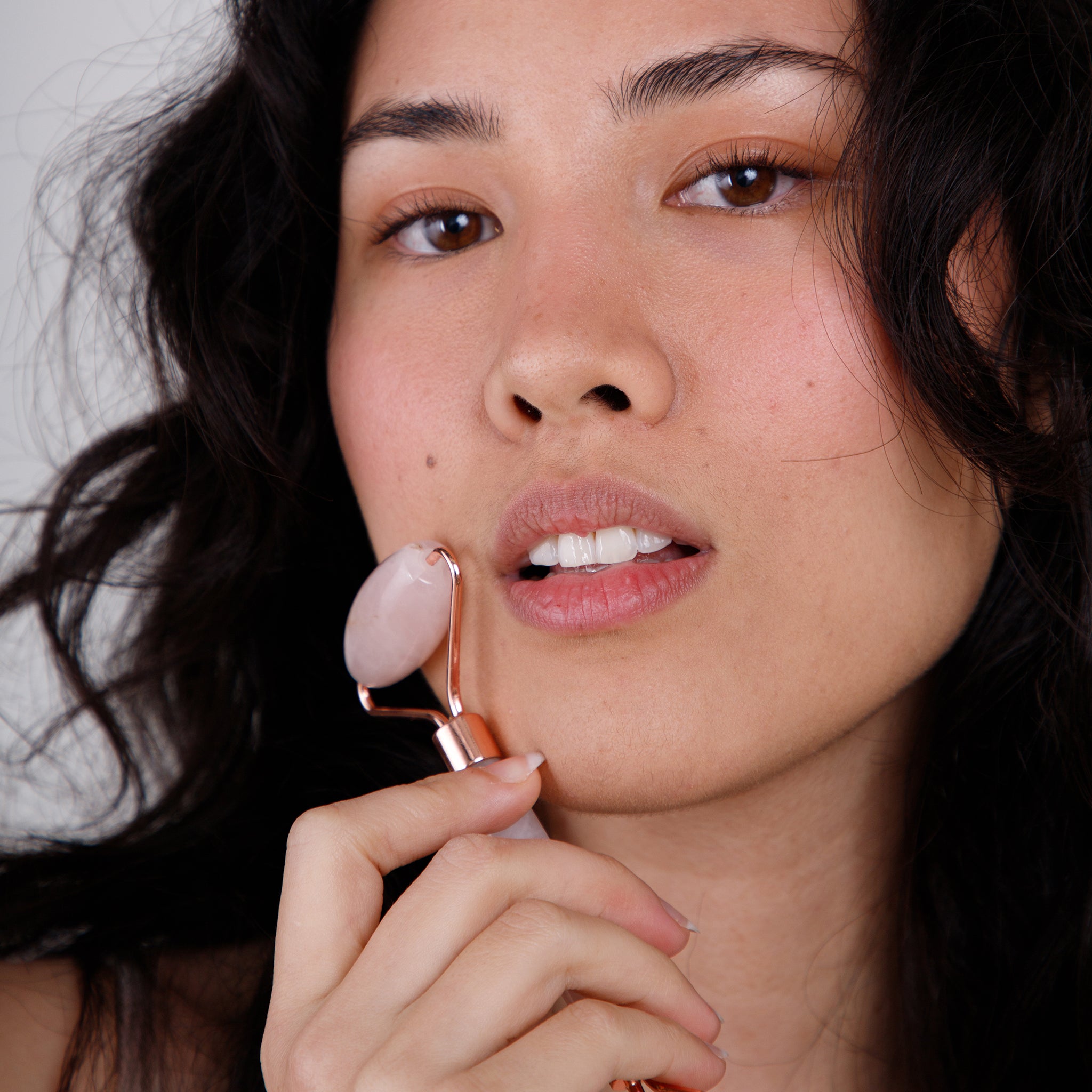 Woman holding rose quartz roller to face
