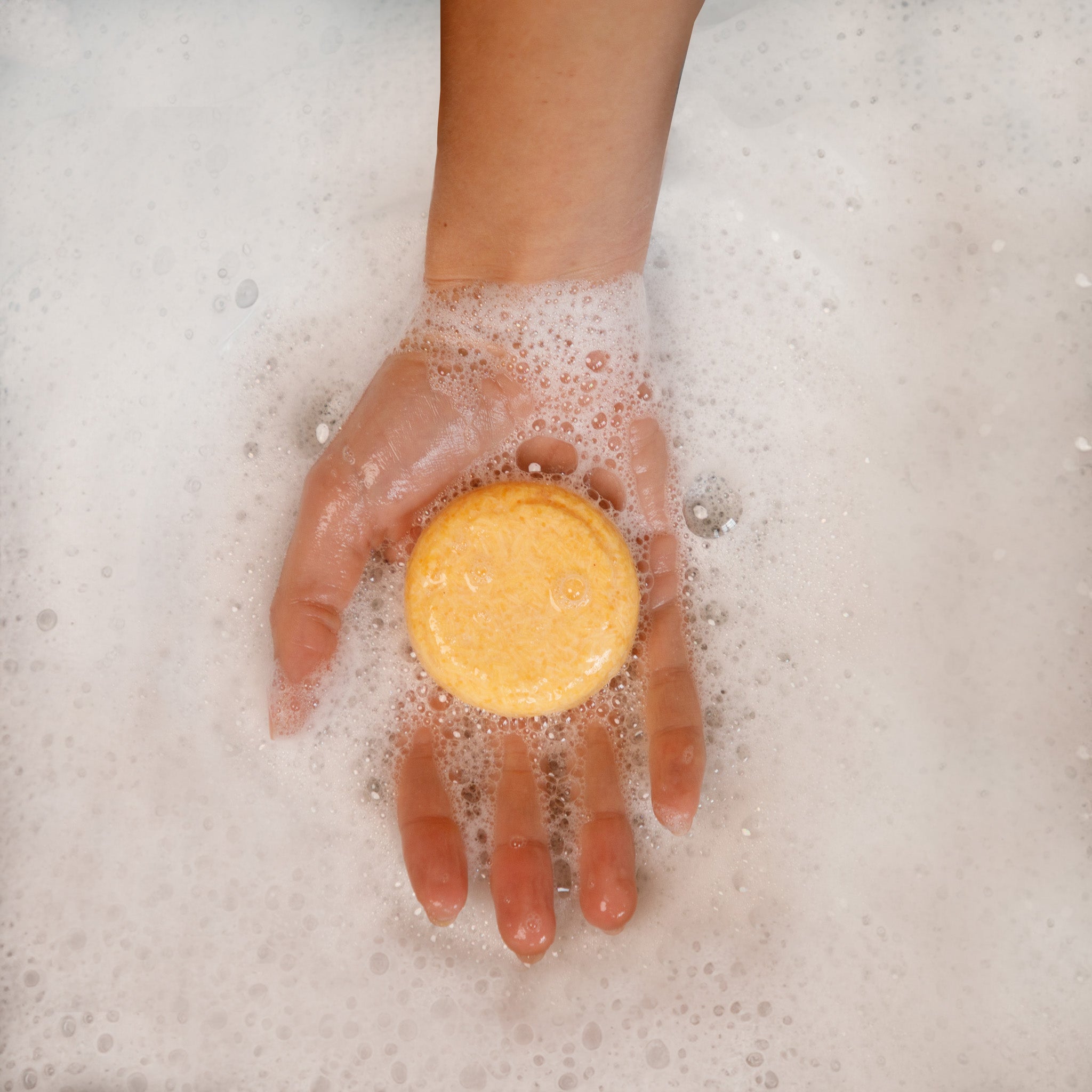 a hand holding a shampoo bar without sodium lauryl sulfate