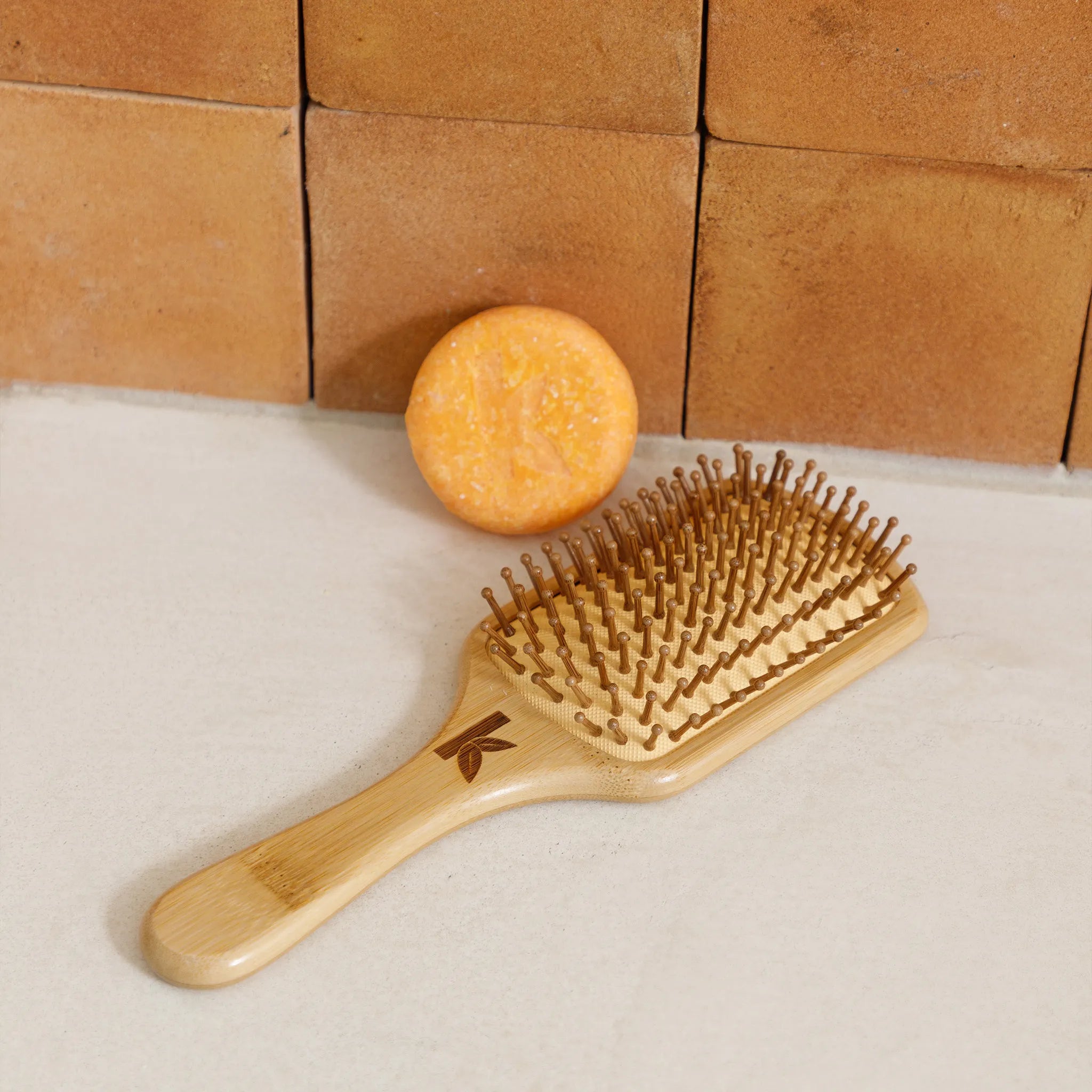 Wooden hairbrush and honey soap on a tiled bathroom