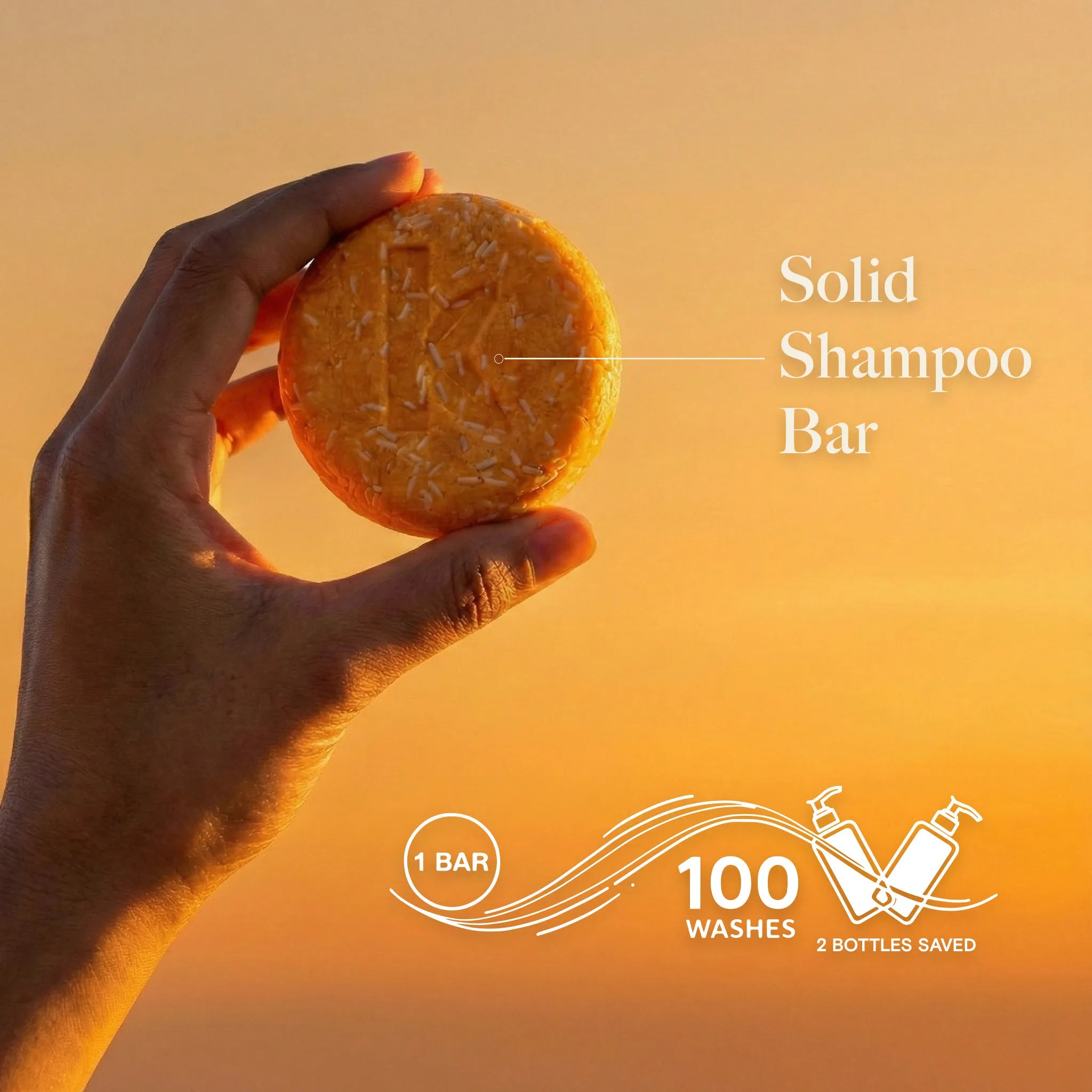 Hand holding a solid honey shampoo bar with sunset background