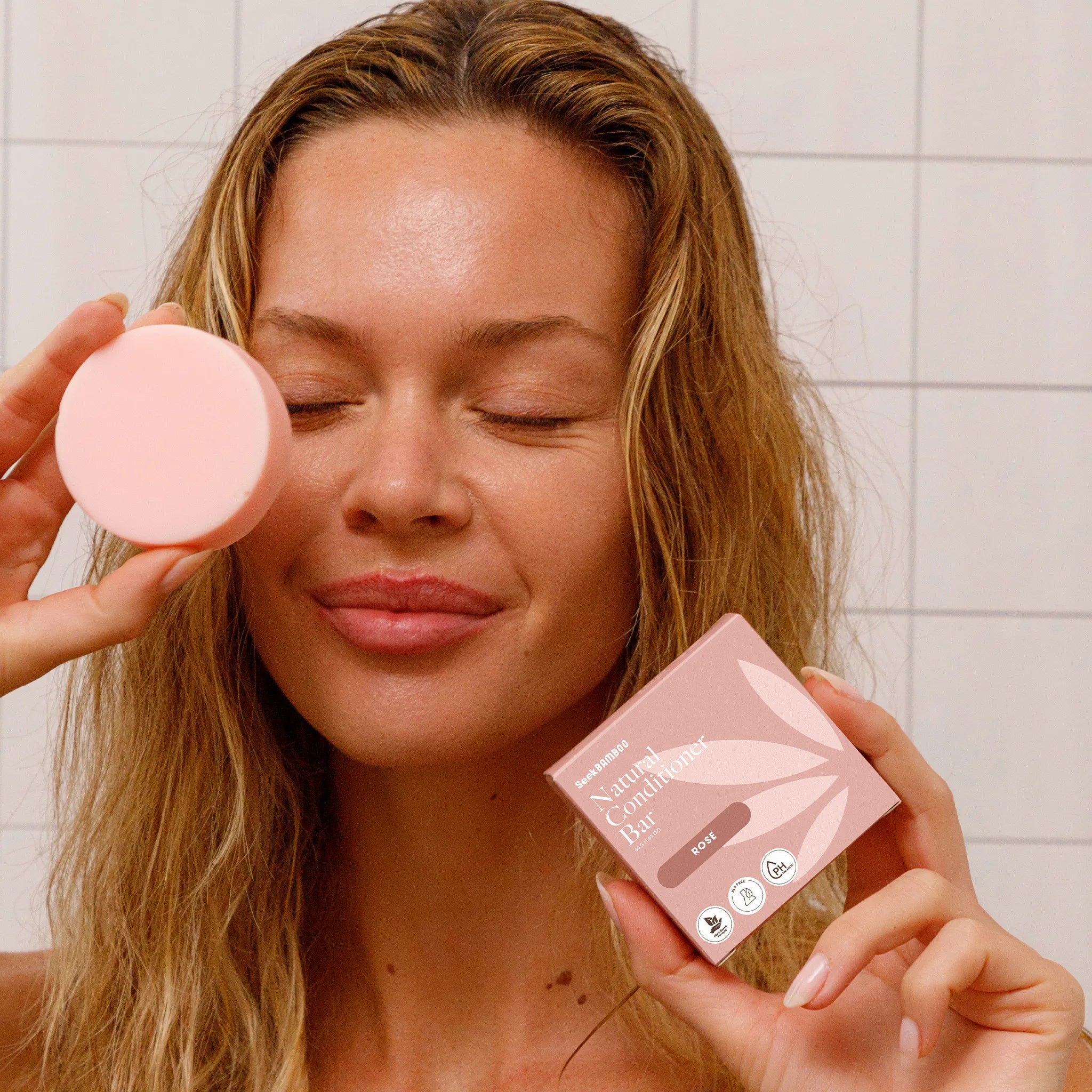 Woman displaying  rose conditioner with seek bamboo box.