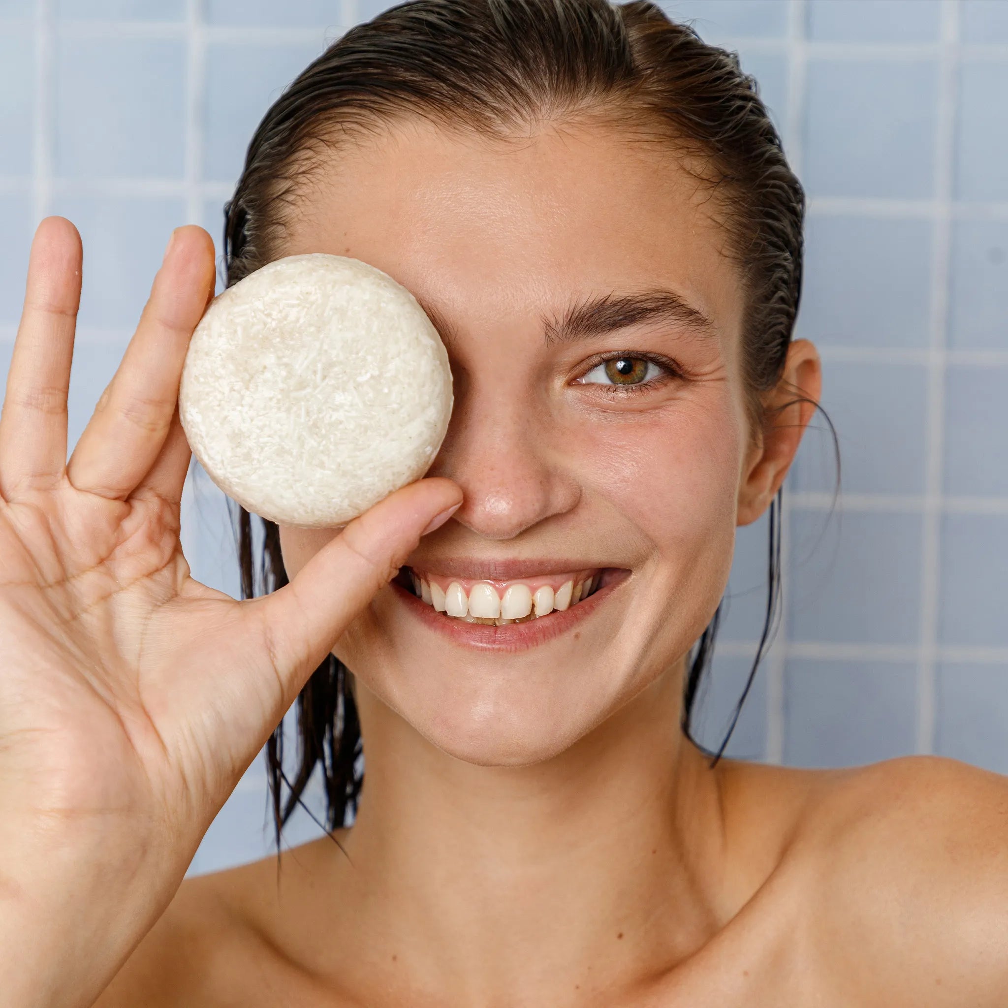 a woman holding a rosemary shampoo bar over her eye from seek bamboo