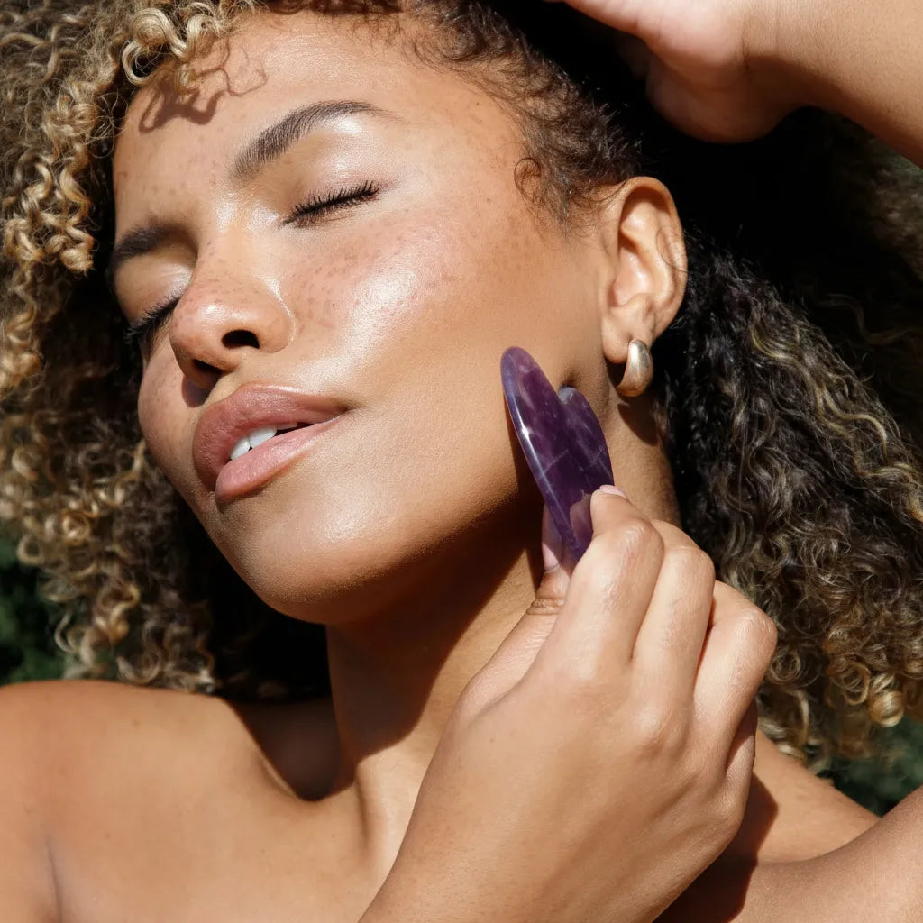 woman using Seek Bamboo Amethyst Gua Sha on face
