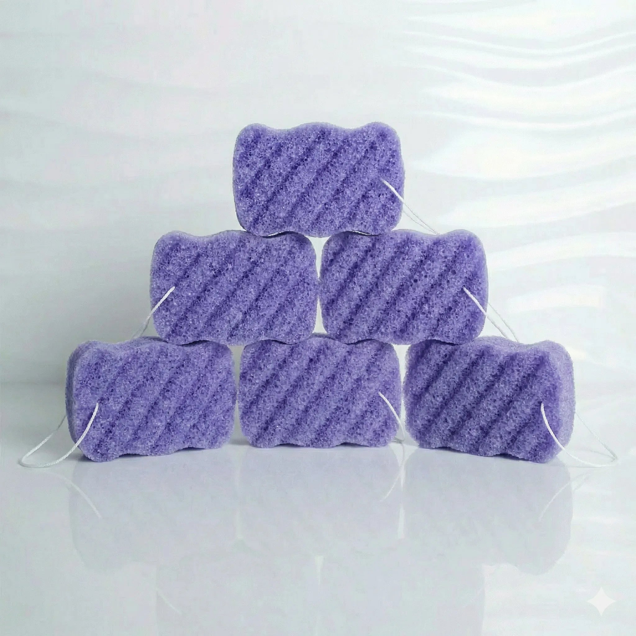 Six lavender konjac body sponges stacked on a white background