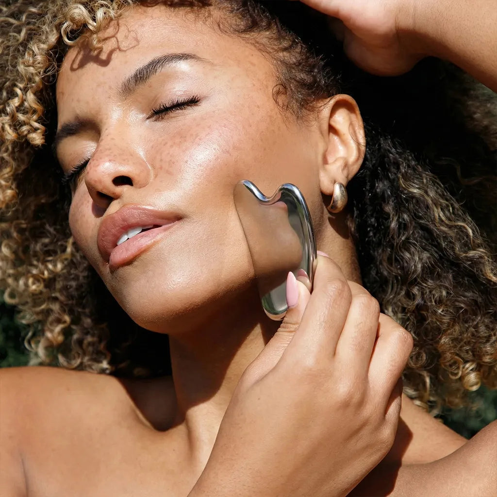 Woman using a skincare tool on her face outdoors