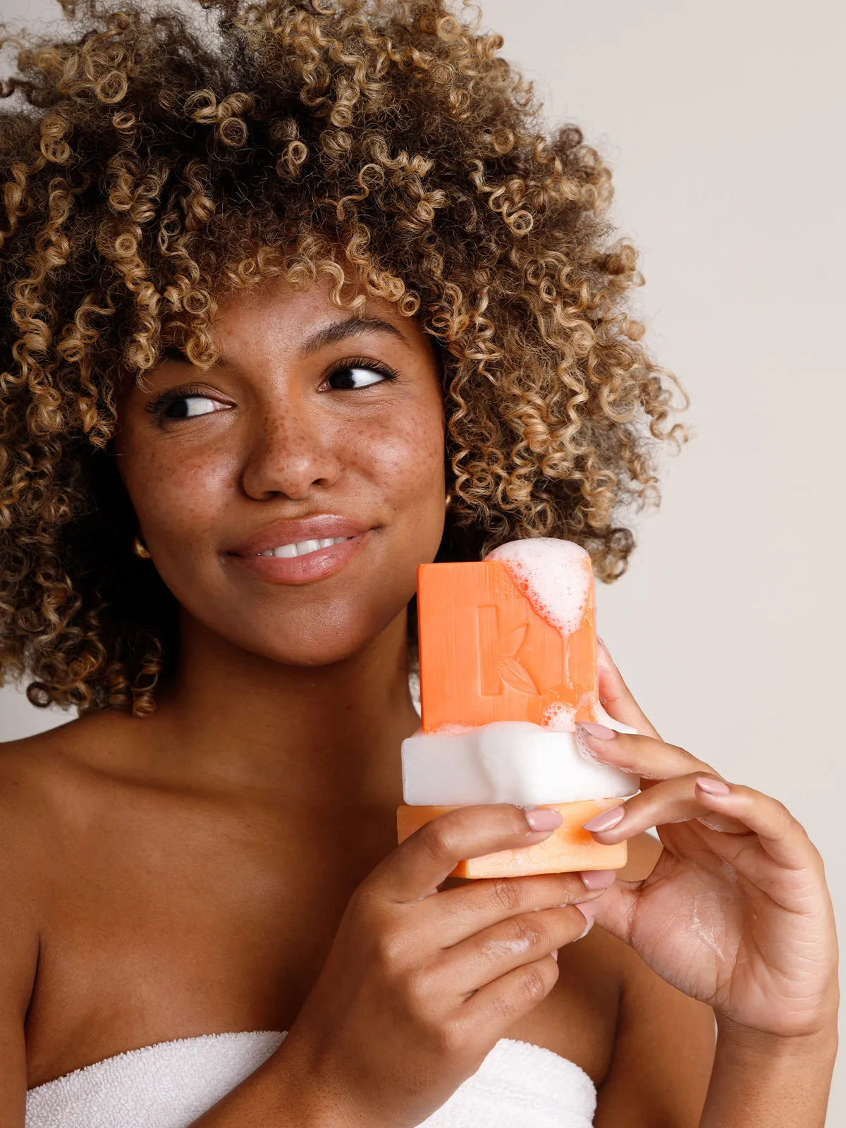 a woman holding a soap stack with honey soap on top for a blog about the benefits of honey soap