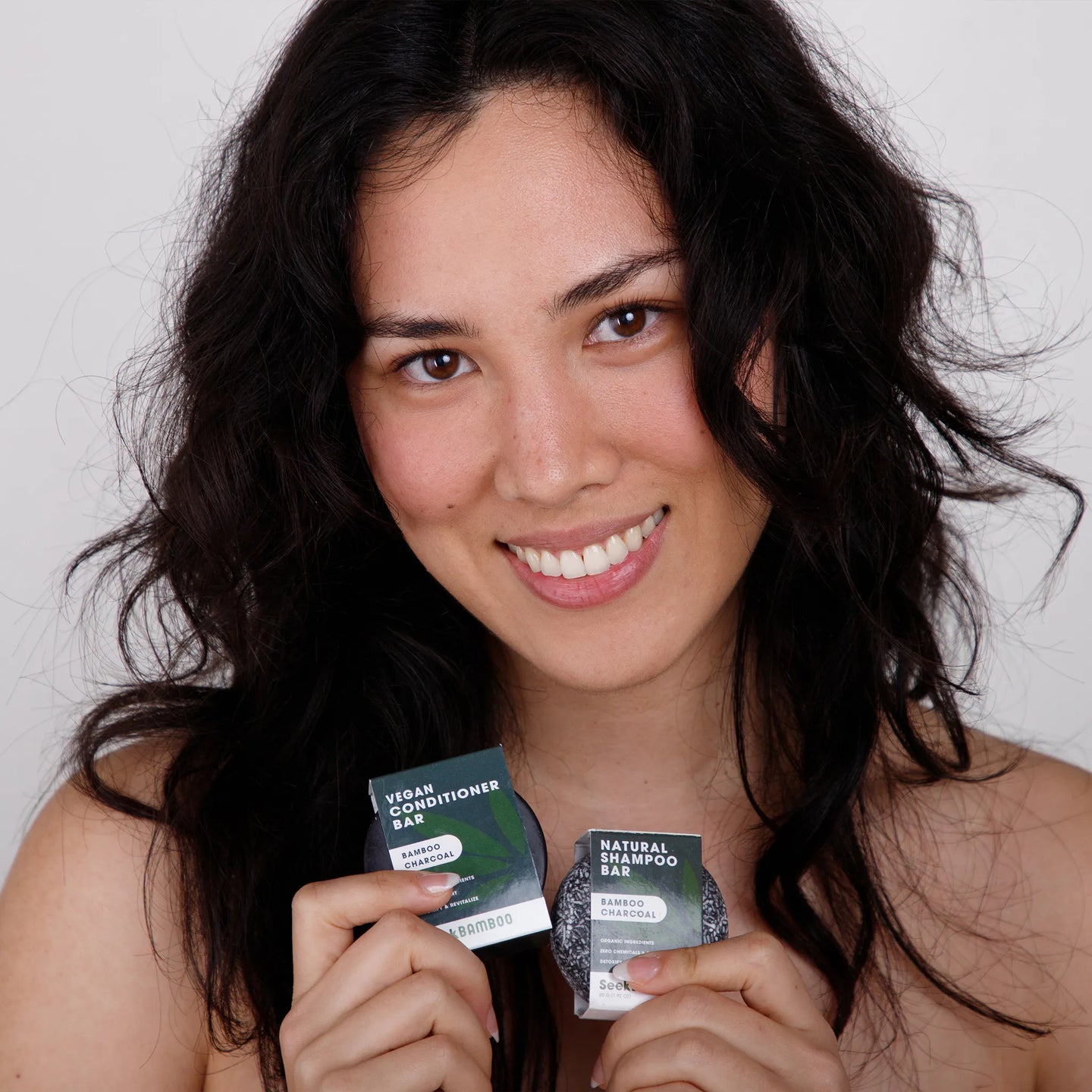 woman holding charcoal shampoo and conditioner