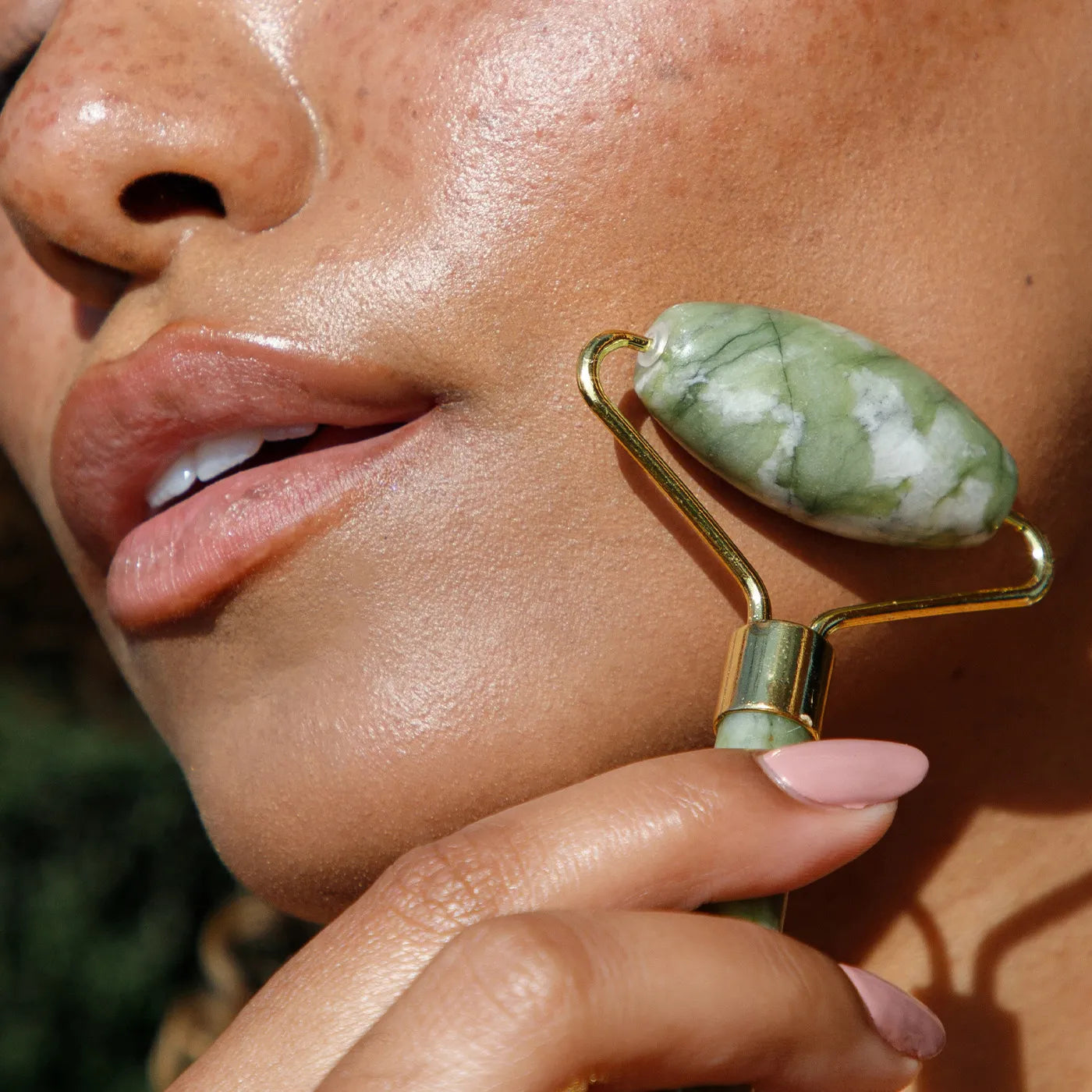 close up of a woman using a jade roller in a blog photo for how to use a jade roller