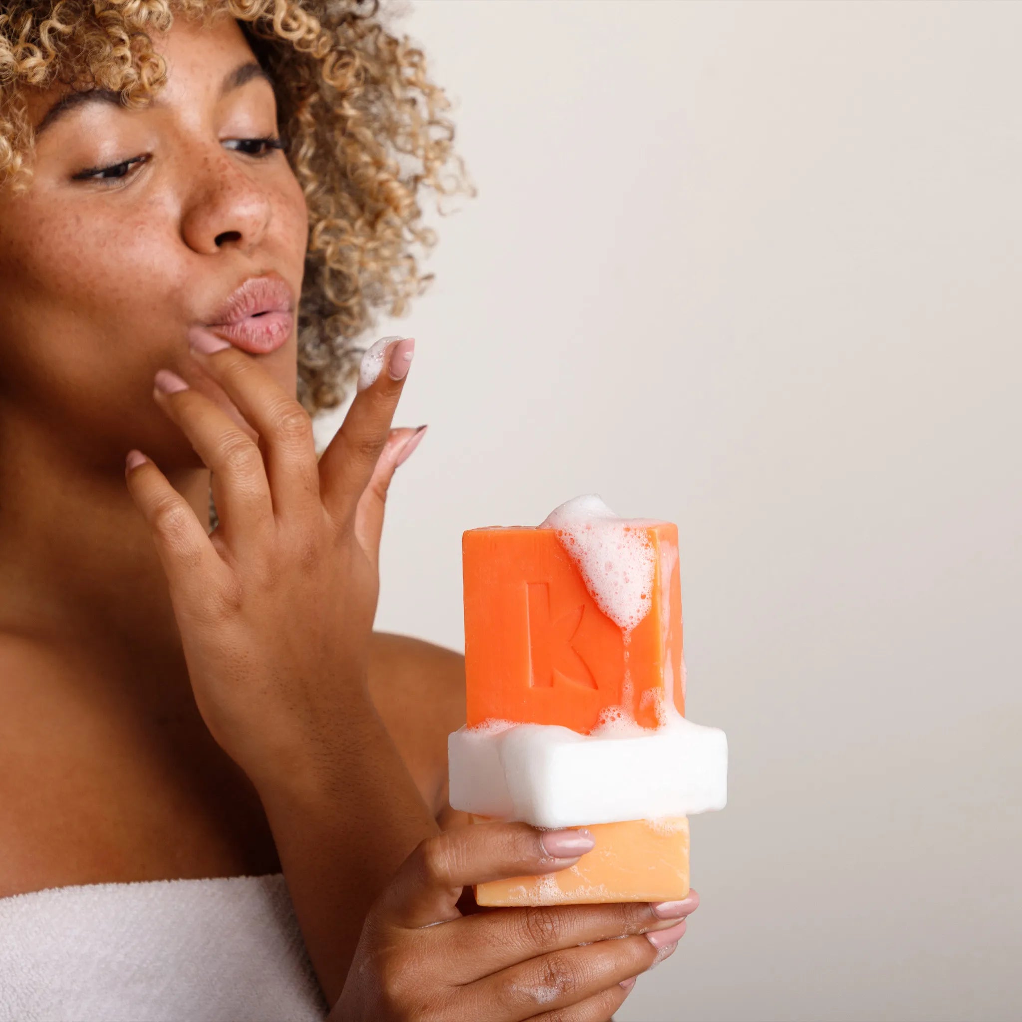 a woman holding kojic acid and turmeric bar soaps