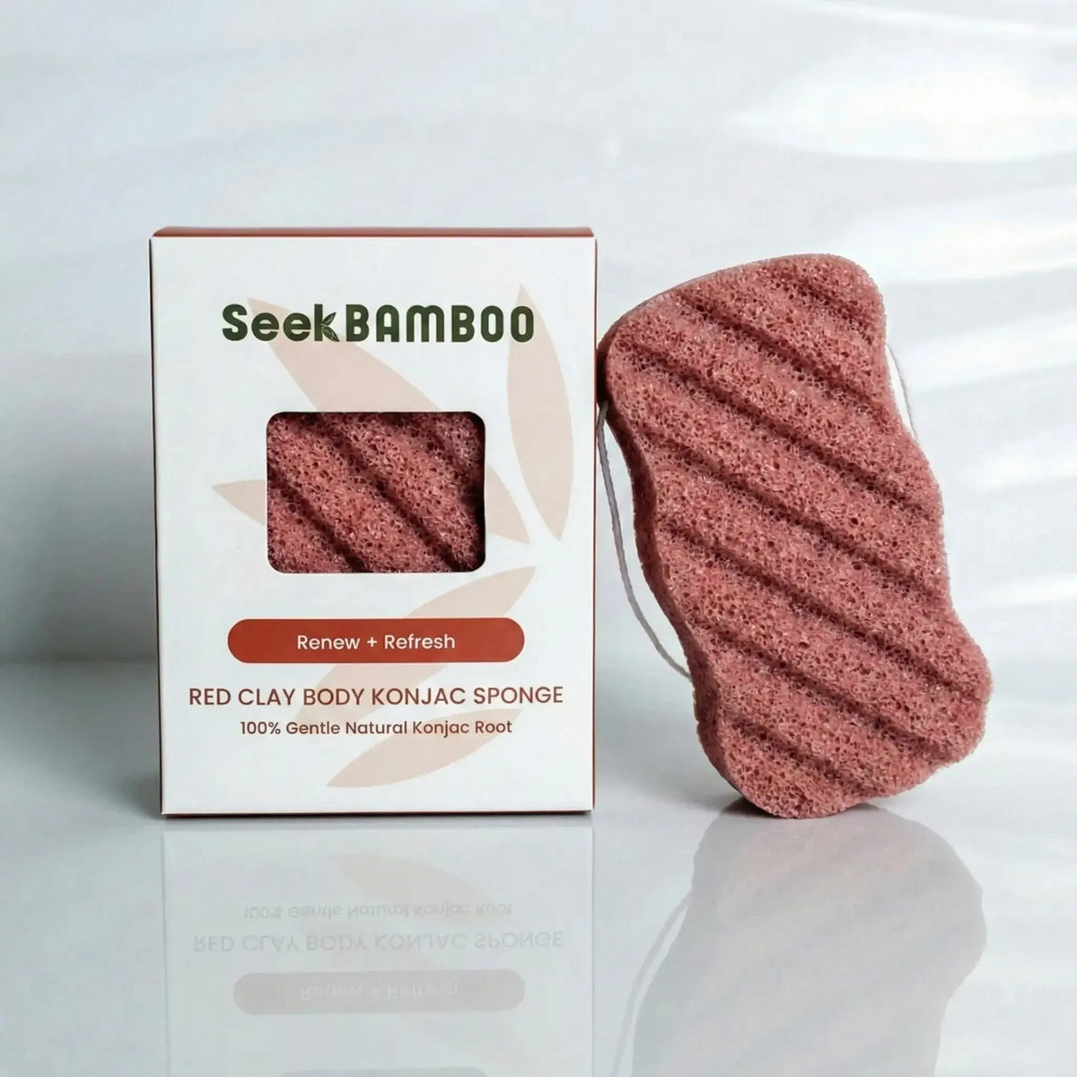 Seek Bamboo red clay body konjac sponge shown next to its white product box on a light gray reflective surface.