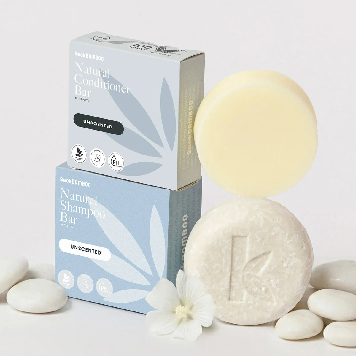 shampoo and conditioner bar fragrance-free with packaging and white flowers on a light background