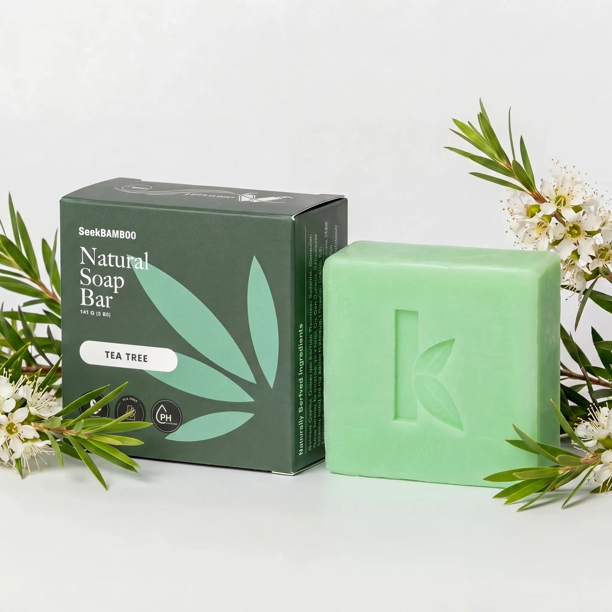 natural tea tree oil soap bar and packaging with tea tree leaves on a light background